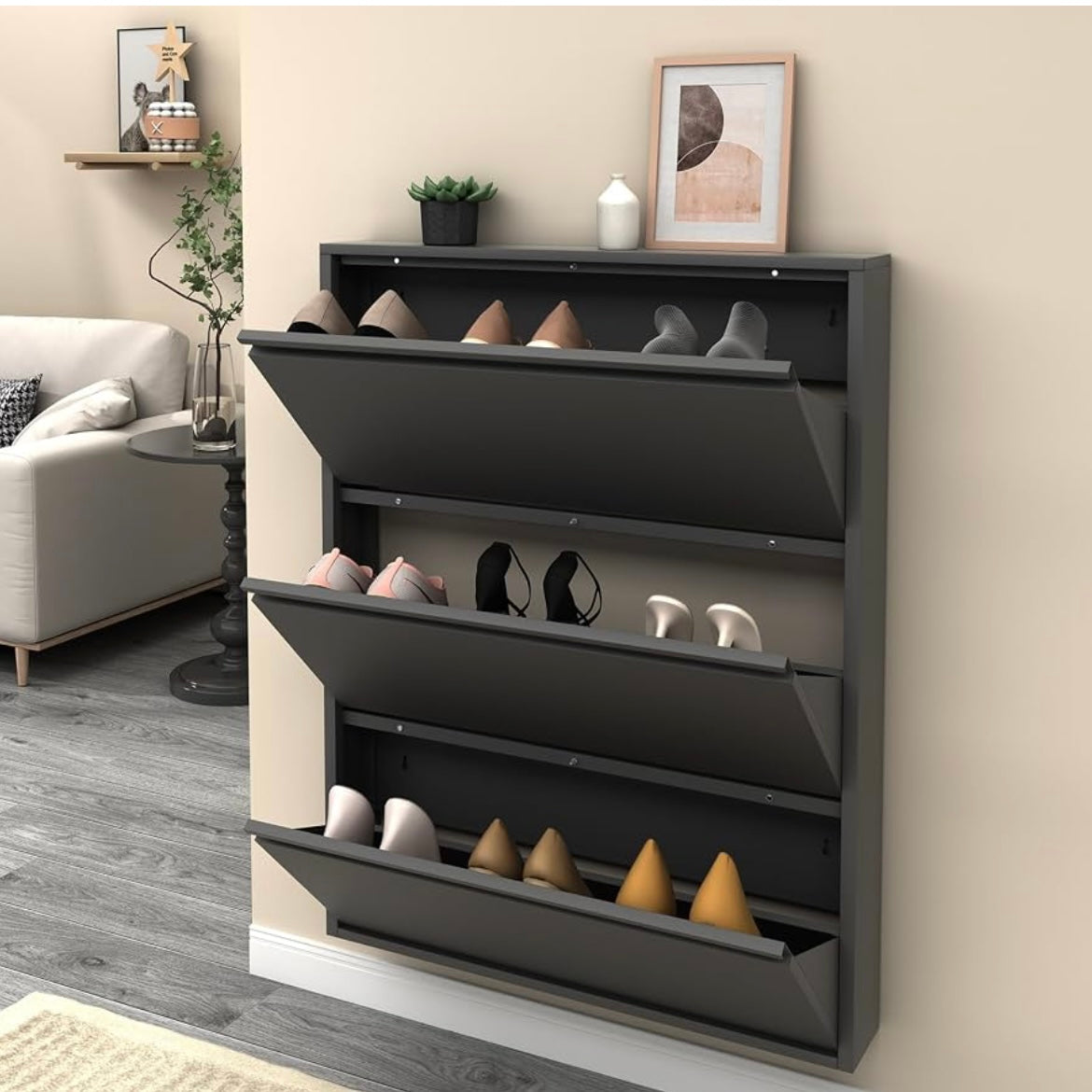 Black slim shoe cabinet with three open flip-down drawers holding heels and everyday shoes.