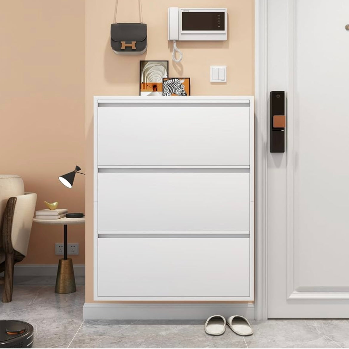 White slim shoe storage cabinet with three flip-down drawers beside an entryway door.